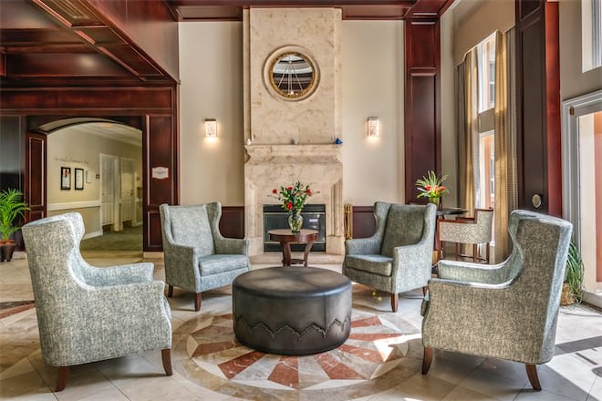 A luxurious lobby featuring elegant armchairs arranged around a circular table, centered by a fireplace with modern decor.