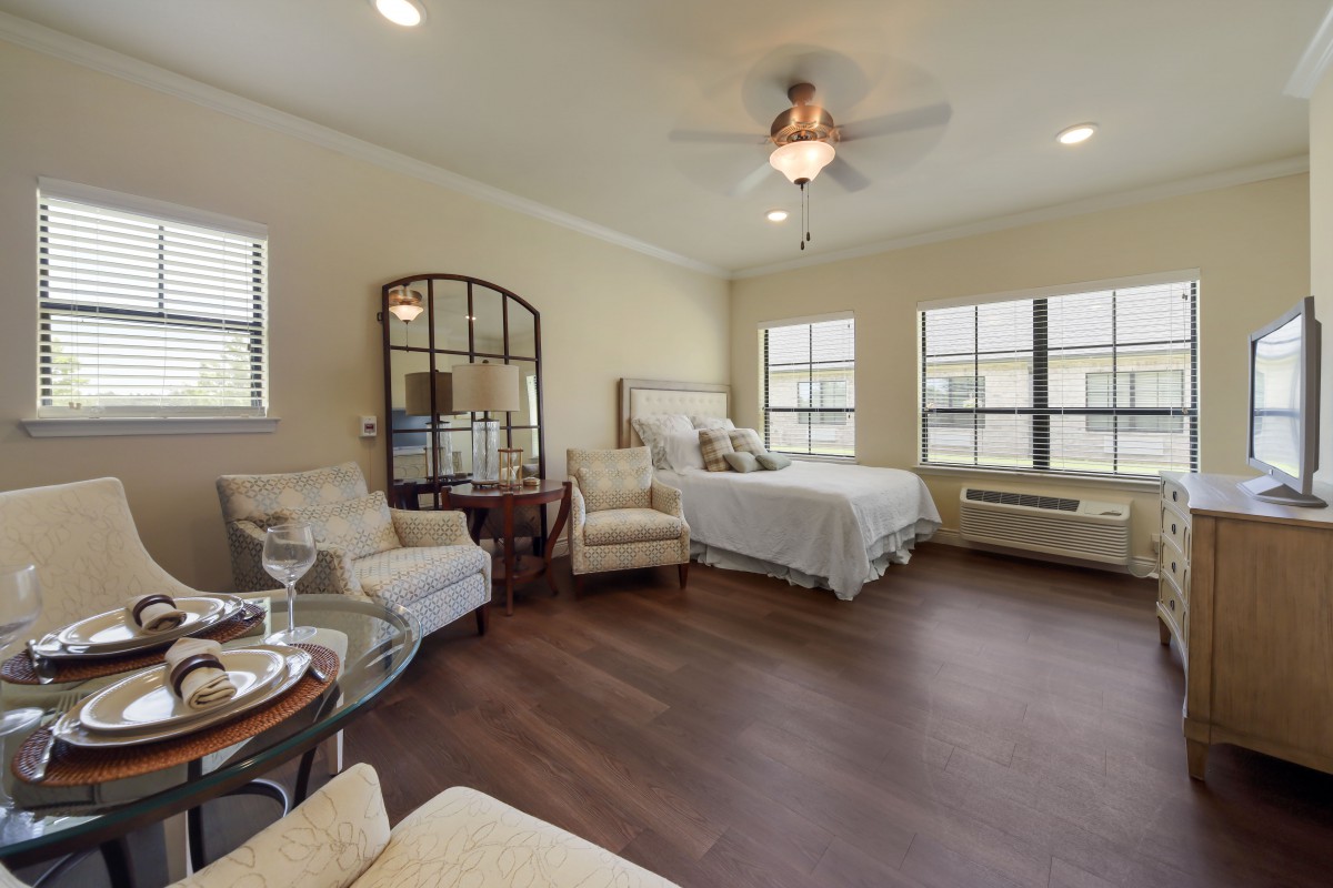 A spacious bedroom with elegant decor, featuring a comfortable bed, armchairs, and large windows that allow natural light to fill the room.