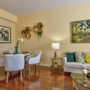 A cozy living and dining area with elegant decor, featuring comfortable seating, art pieces, and warm lighting.