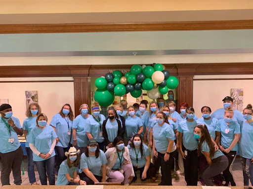 Team gathering with a vibrant balloon backdrop, celebrating together while staying safe.