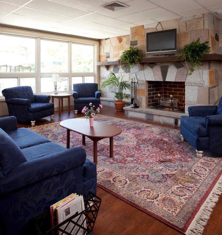 A cozy living room featuring blue chairs, a fireplace, and a television.