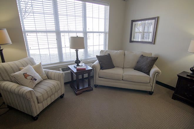 A cozy living room with a sofa, armchair, and a side table next to a large window.