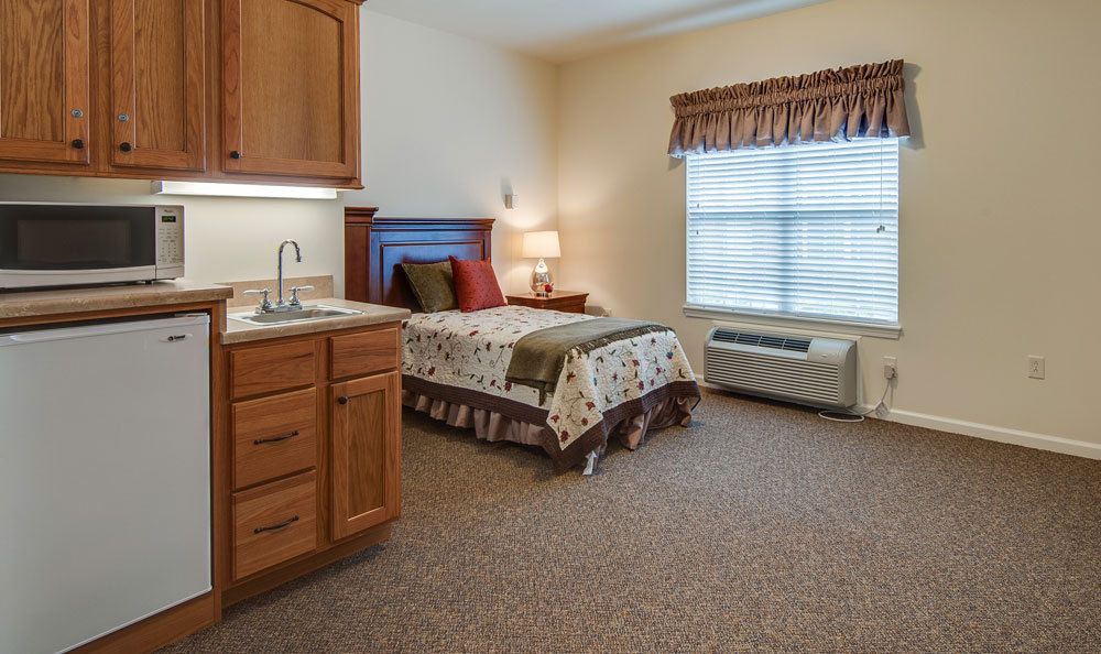 A cozy bedroom with a single bed, wooden cabinetry, and a window with blinds.