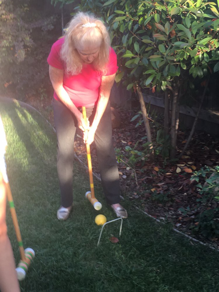 A person playing croquet in a garden setting.