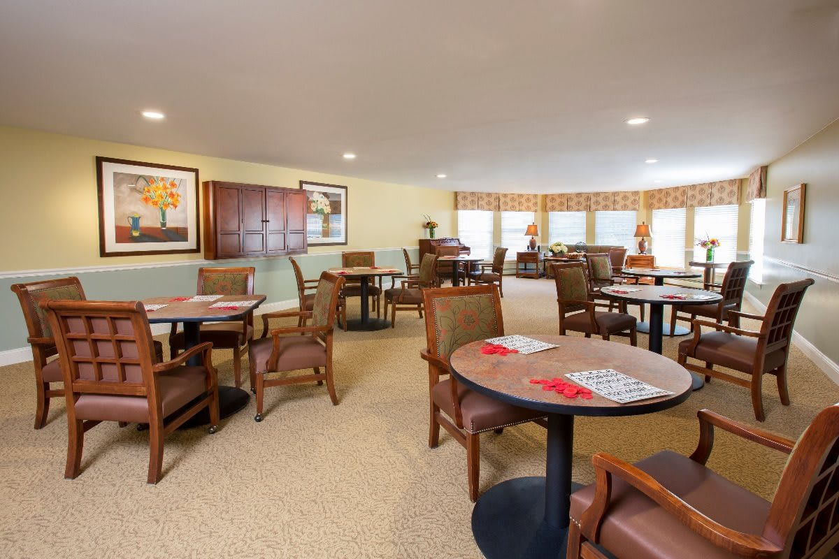 A cozy dining area featuring multiple tables and chairs with soft lighting.