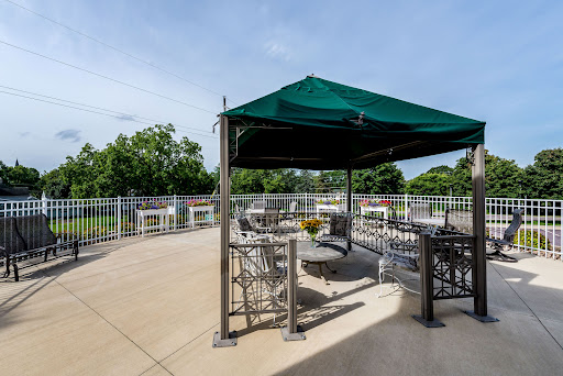 A serene outdoor patio area featuring a green canopy and seating arrangements, perfect for relaxation and gatherings.