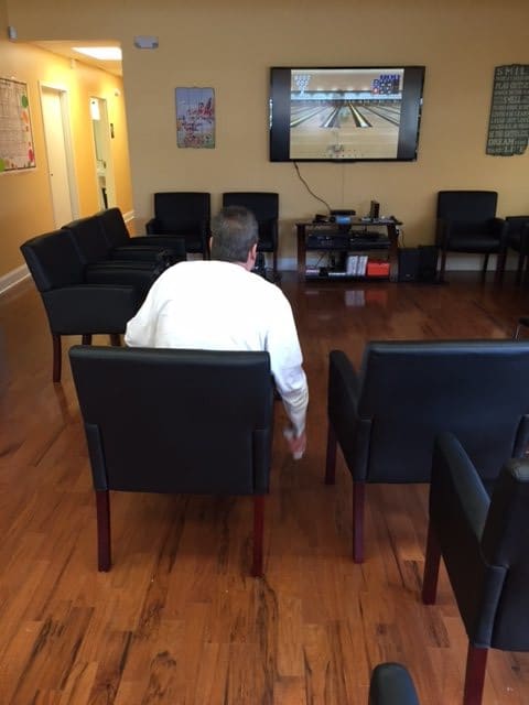 A person sitting in a waiting room with chairs and a television on the wall.