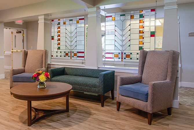 A cozy living room with stylish furniture and decorative stained glass windows.