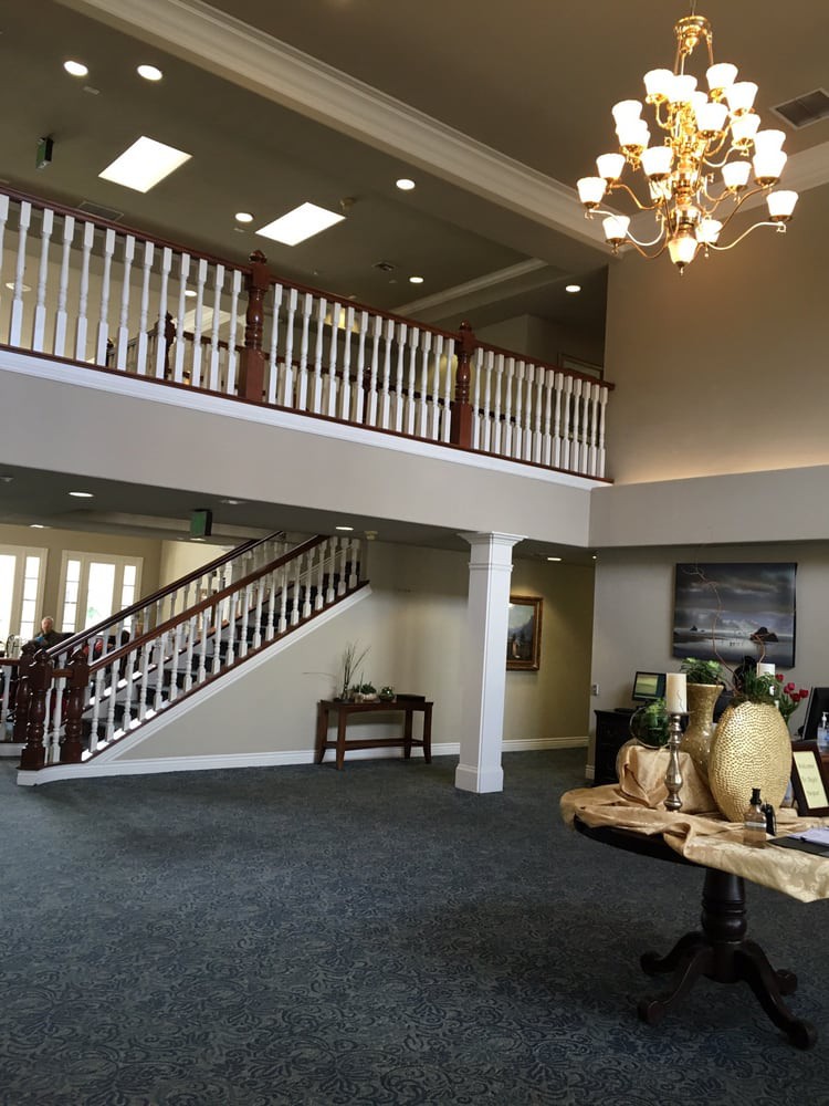 Spacious lobby with a grand staircase and elegant chandelier.