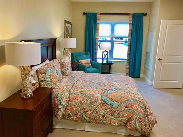A cozy bedroom with colorful bedding and vibrant curtains.