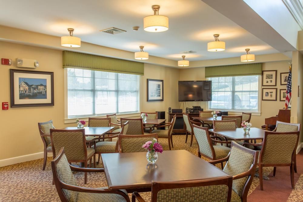 A well-lit dining area with multiple tables and chairs arranged neatly, featuring large windows and modern decor.