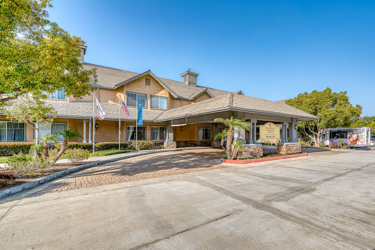 A hotel entrance with a covered driveway and landscaped surroundings.