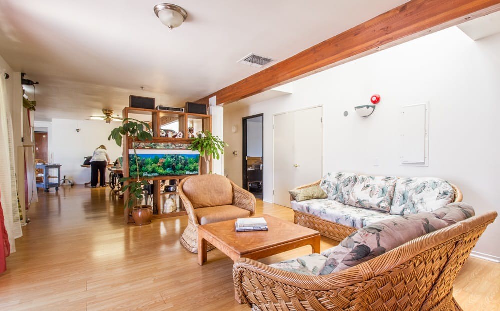 A cozy living room with wicker furniture and a large aquarium.