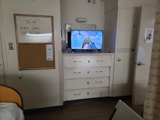 A view of a room featuring a television mounted above a dresser.