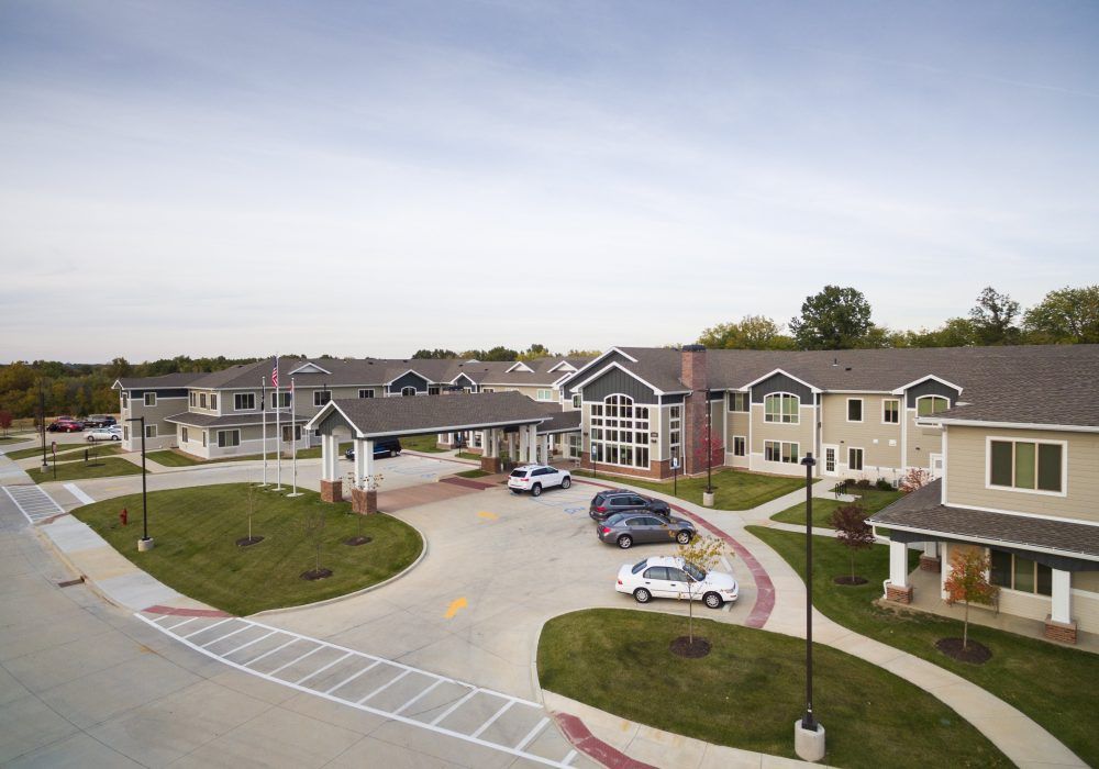 A residential building with a parking lot and several parked vehicles in a suburban area.