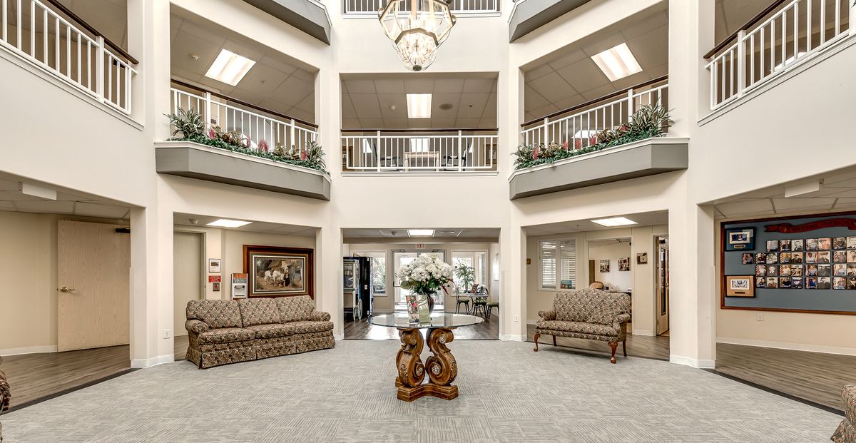 A spacious and elegantly designed lobby with sofas, a central round table, and a chandelier.