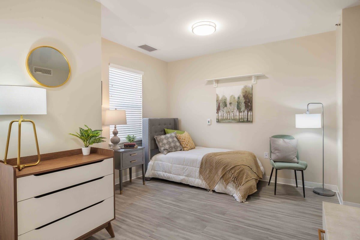 A modern bedroom with stylish decor, featuring a bed, dresser, and artwork.