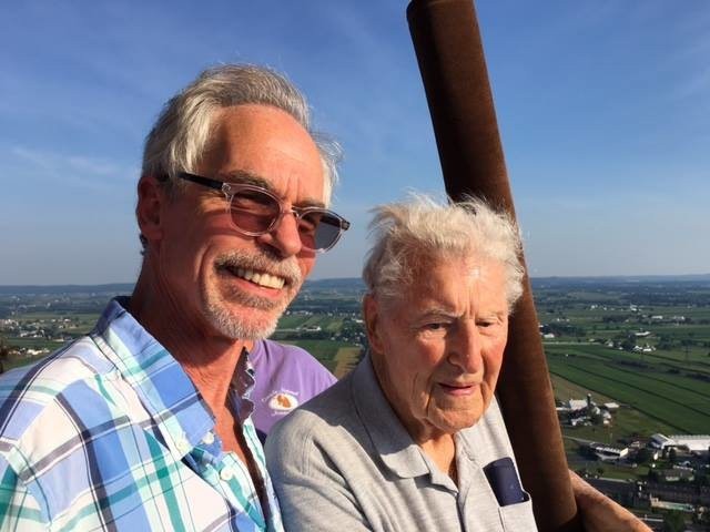 Two people taking a selfie during an outdoor adventure with a scenic view in the background.