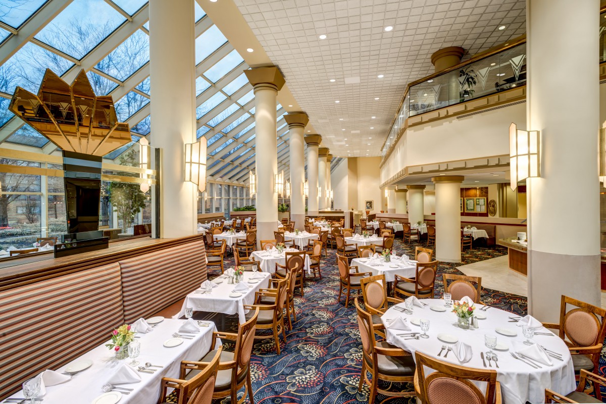An elegant restaurant interior with neatly arranged tables under a large skylight.