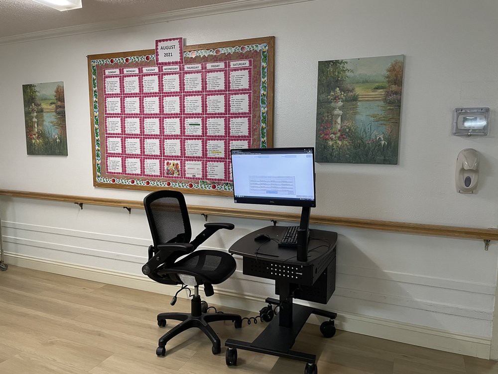 A workspace with a computer station and an office chair, situated next to a bulletin board and wall art.