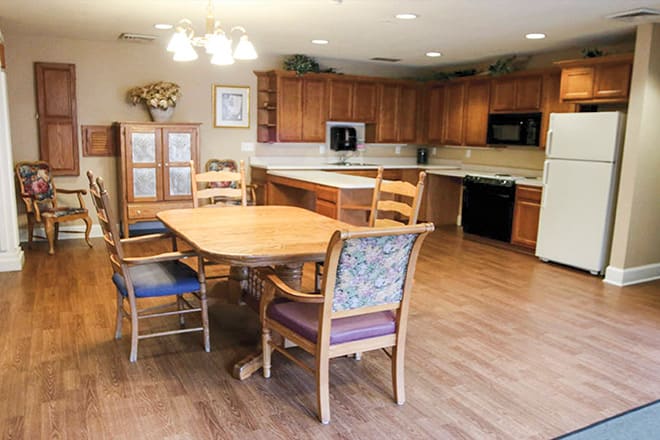 A spacious kitchen with wooden cabinets, a dining table, and chairs on a wooden floor.