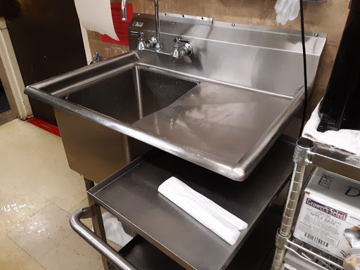 A stainless steel sink in a commercial kitchen setting, equipped for food preparation.