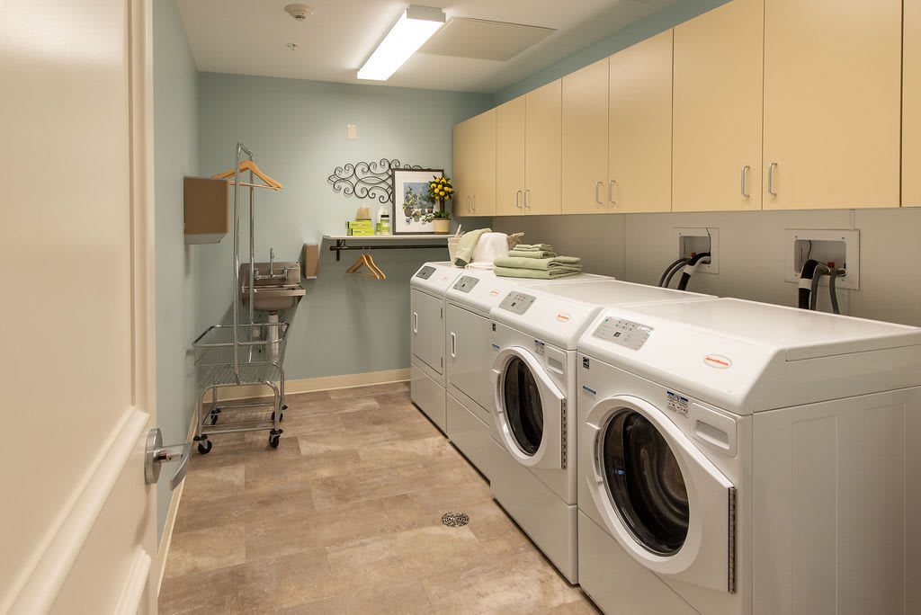 A neatly organized laundry room with washing machines, dryers, and storage cabinets.