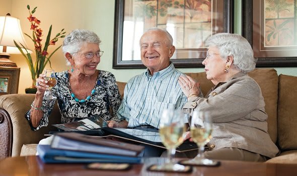 Three seniors enjoying a cheerful conversation indoors.