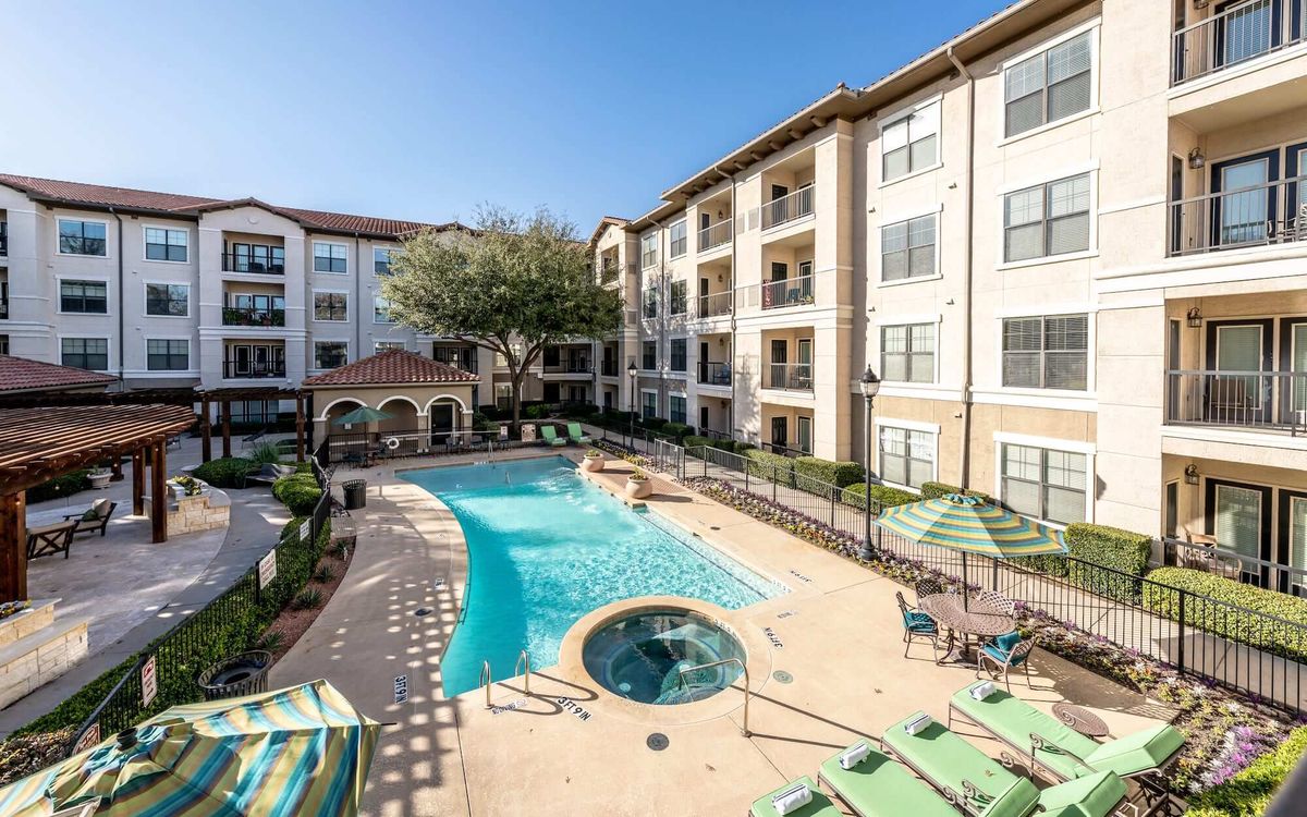 A sunny day at a residential apartment complex featuring a swimming pool and outdoor seating area.