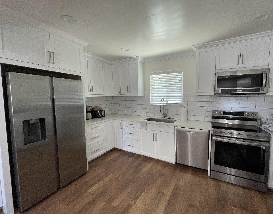 A modern kitchen featuring white cabinets and stainless steel appliances.