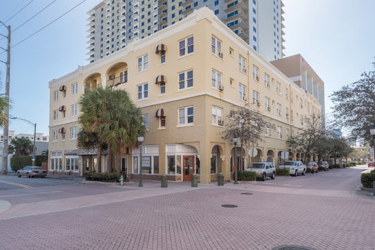 A corner view of a yellow residential building in an urban setting.