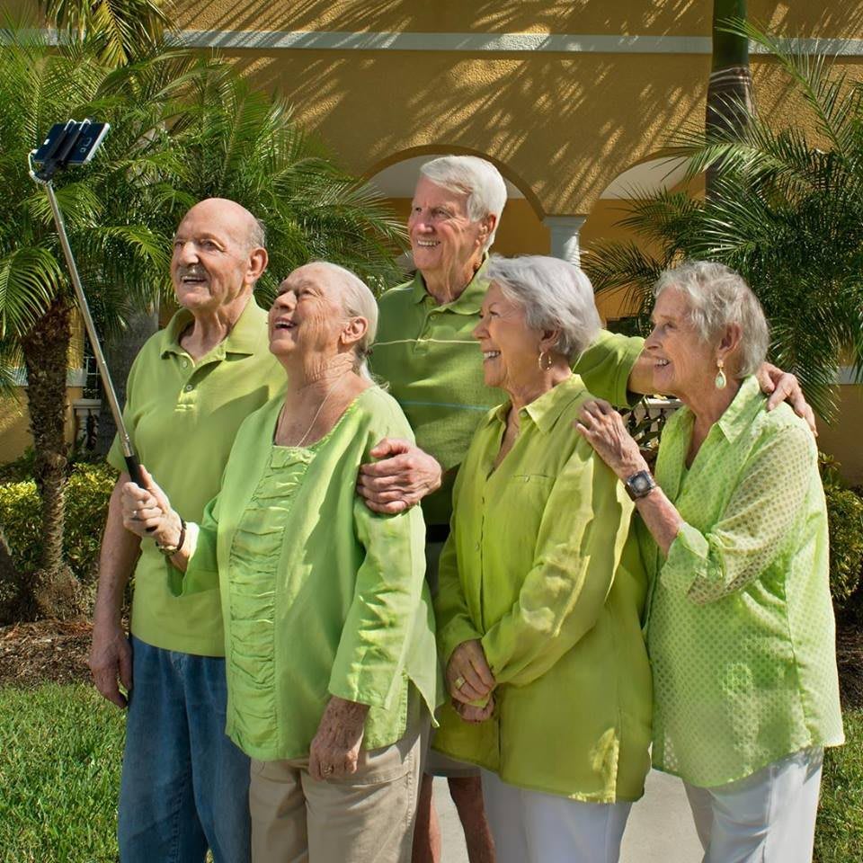 A group of seniors taking a selfie outdoors, all dressed in green.
