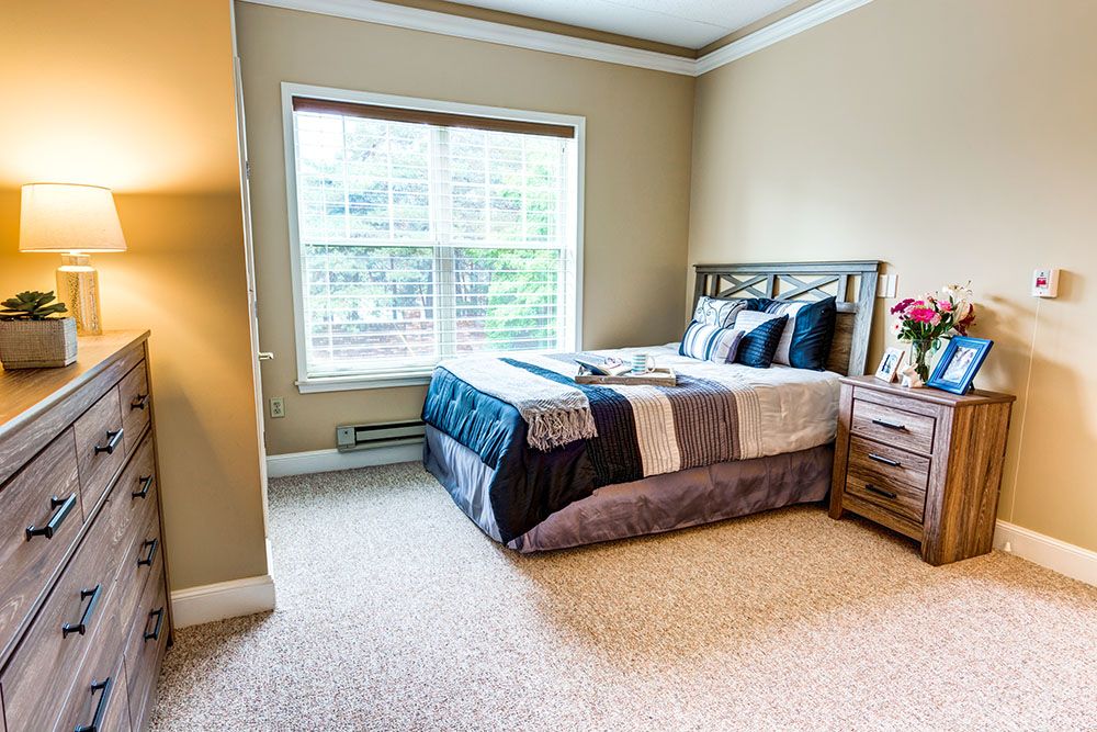 A cozy bedroom featuring a neatly made bed beside a window with ample natural light.