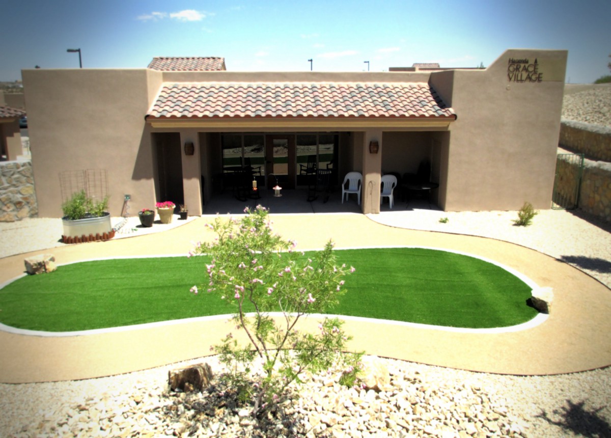 A southwestern-style house with a desert landscape and artificial turf in the yard.
