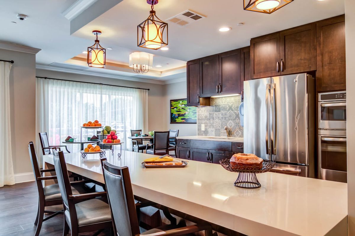 A modern kitchen with an island, pendant lights, and stainless steel appliances.