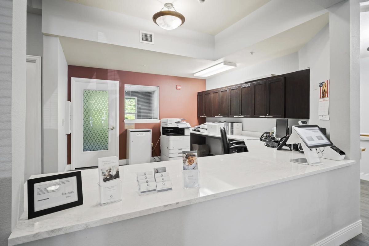 A modern reception area with a sleek white desk, office equipment, and dark cabinetry.