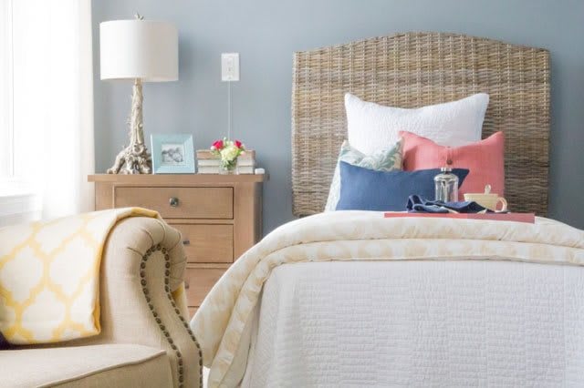 A cozy bedroom with a neatly made bed and a wooden nightstand.