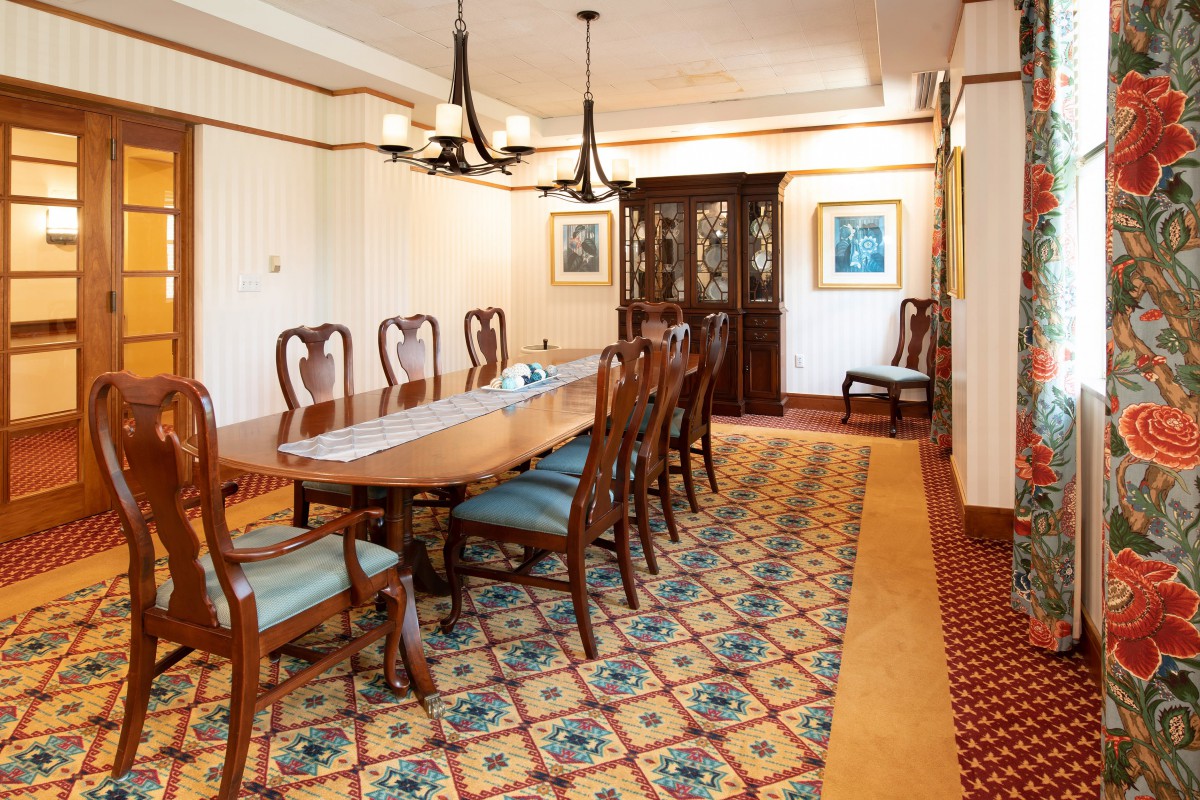 Elegant dining room with a long table, chairs, and chandeliers.