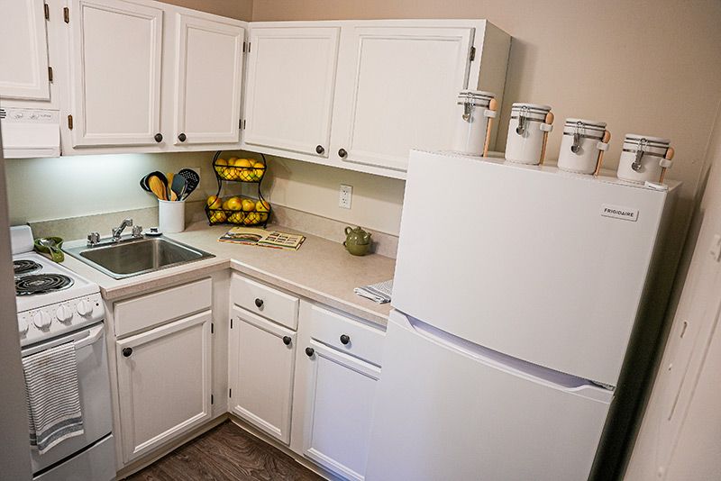 A clean and organized kitchen with white cabinets and appliances.