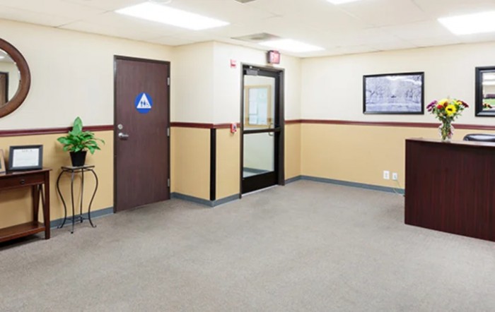 An empty office waiting area with a carpeted floor and doors leading to other rooms.