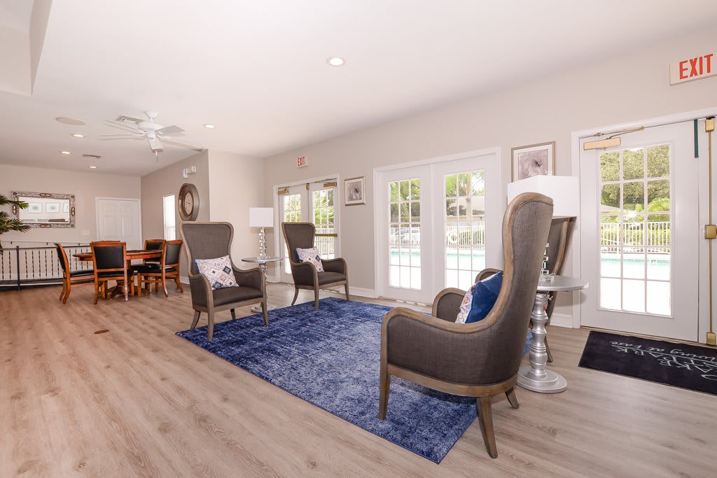 A modern living room featuring armchairs, a blue rug, and wooden floors.