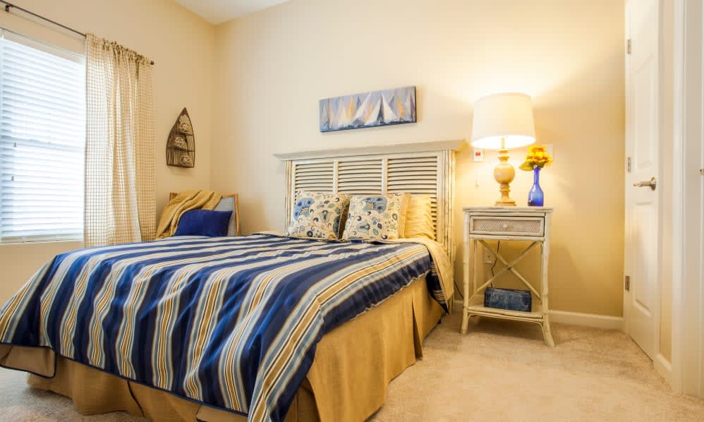 A cozy bedroom with a double bed, blue and yellow bedding, and a stylish nightstand with a lamp.