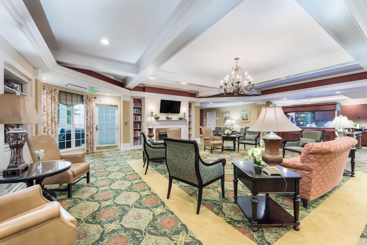 A well-furnished living room with elegant decor, featuring comfortable seating, a chandelier, and a television.