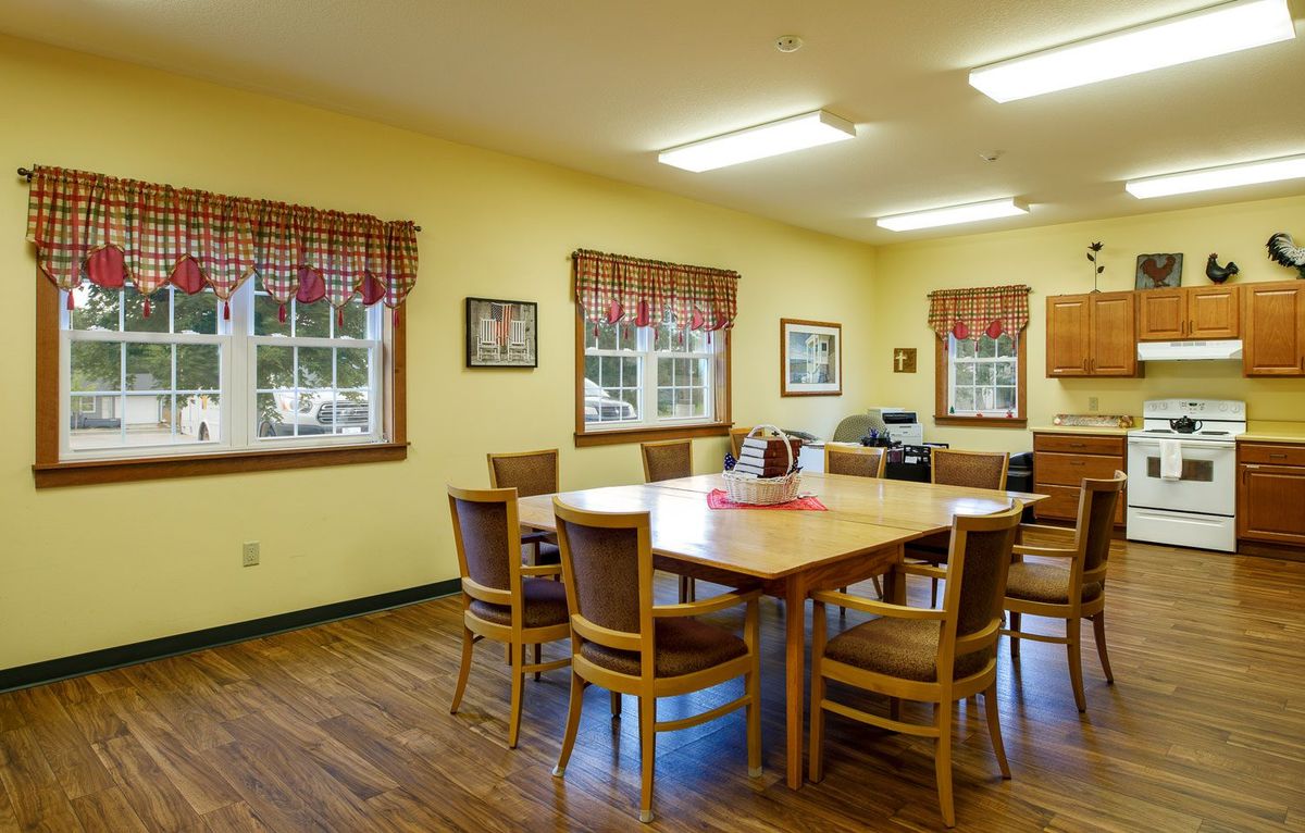 A bright dining room with wooden floors and a large table surrounded by chairs.