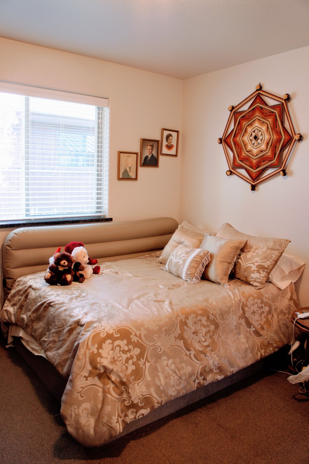A cozy bedroom with a decorated daybed, plush pillows, and teddy bears, featuring wall art and framed photos.