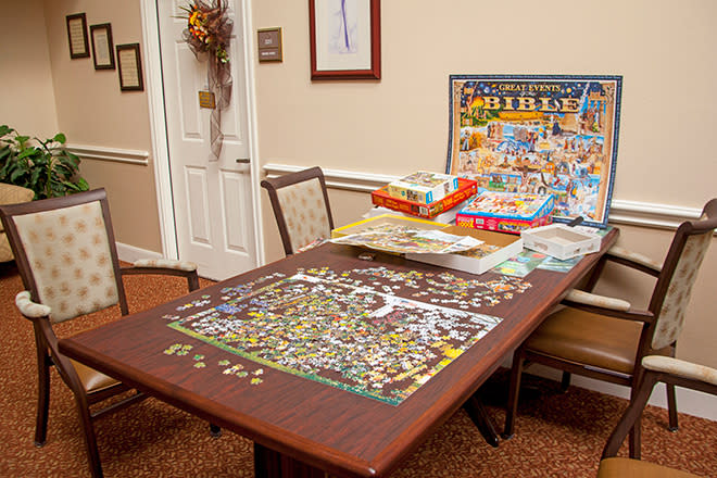 A table with jigsaw puzzles in various stages of completion.