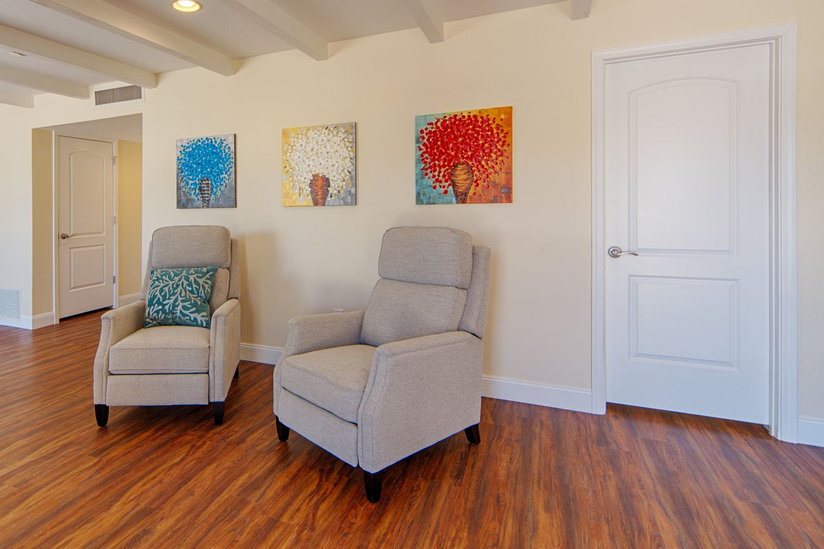 A cozy living room with comfortable armchairs and colorful artwork on the walls.