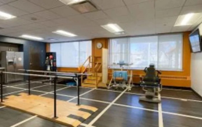 A physical therapy room equipped with various rehabilitation exercise machines and tools.