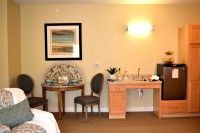 A hotel room interior featuring a desk, chairs, and decorative artwork on the wall.