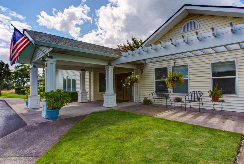 A charming house with a covered porch and well-maintained yard under a partly cloudy sky.